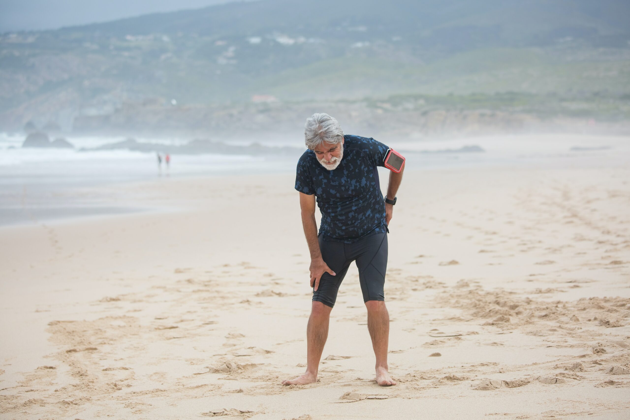 Man on northern beaches sydney showing signs of back pain, by bending over, with arms on lower back. 